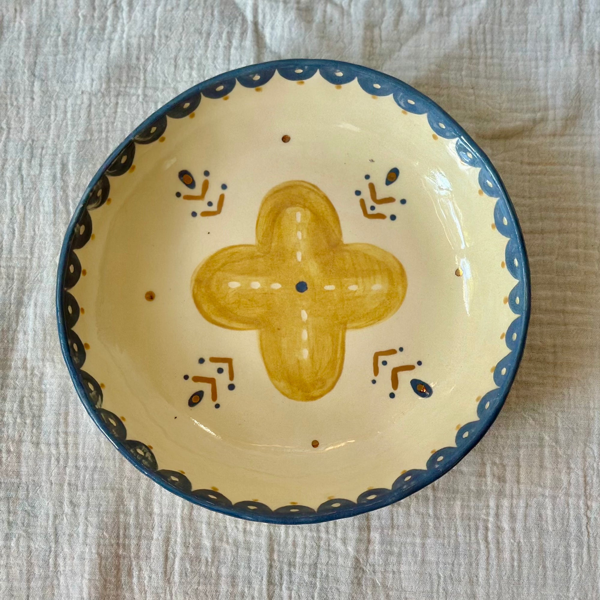 Ceramic bowl with decorative cross design on a textured surface